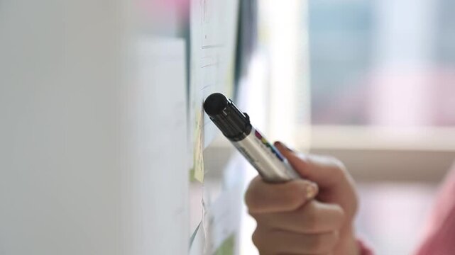 사람 비즈니스 업무 교육 일상 소품 디테일 자재: 실내 사무실 화이트보드판 앞에서 검은색 보드마카 펜을 손에 쥐고 포인트를 짚거나 설명하려는 순간을 포착한 디테일 초근접 클로즈업 동영상 클립입니다.