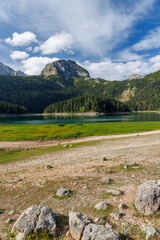 Obraz premium Calm lake with forest reflection under blue sky