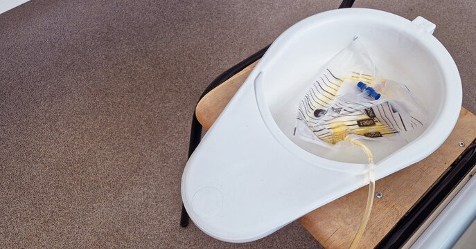 A urinal by the patient's bedside in a hospital room setting.