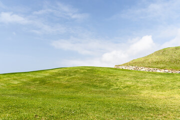 Obraz premium Green grass hill under blue sky minimal landscape background