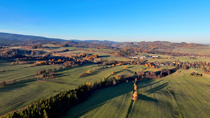Landscape aerial autumn Jeseniky fall Dolni Moravice drone captures dramatic countryside fields forest sunny day photograph lush green hills pastures vibrant golden autumn scene colored trees © Tomas Vynikal