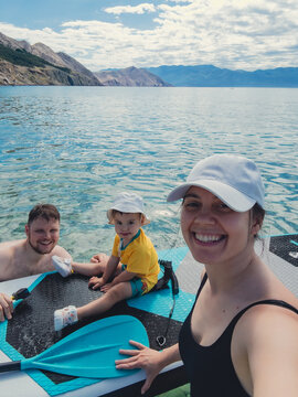 Family selfie on paddleboard by clear mountain lake