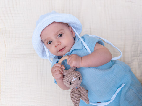 Baby in blue outfit holding knitted bunny toy portrait