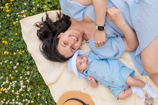 Mother and baby relaxing on blanket in green grass overhead