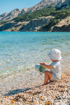 Toddler playing on pebble beach by clear lake