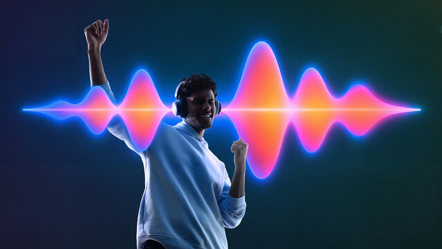 Young man dancing with headphones and colorful sound wave visualizer in neon light. Concept of music streaming service, wireless audio tech, digital entertainment and ad campaign.