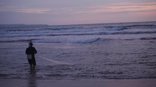 Fisherman casting a net into the ocean at dusk