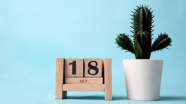Month of July wooden block calendar on a light blue background
