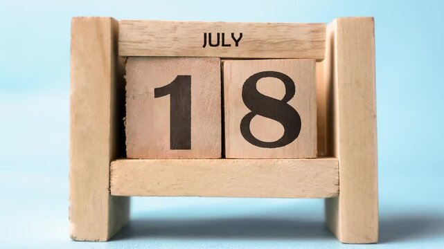 Month of July wooden block calendar on a light blue background