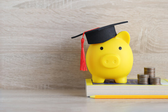 Yellow piggy bank with a graduation cap on a book and coin stacks, symbolizing saving money for education and future financial planning for students.