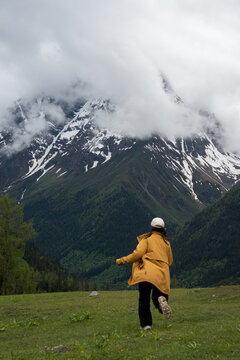 The female traveler runs toward the snow-capped mountains
