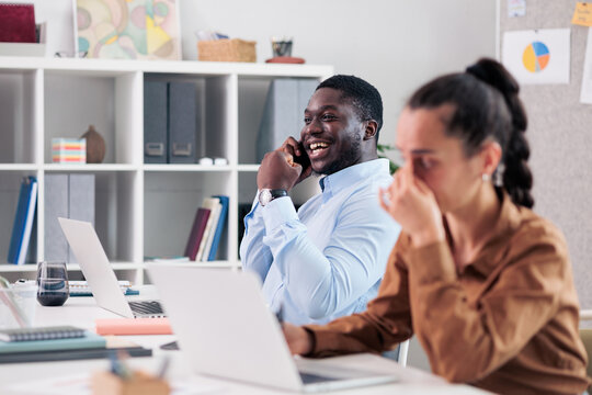 Coworker on phone distracting stressed woman in shared office