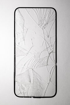 Close-up of shattered smartphone screen with spiderweb-like cracks