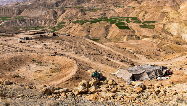 Traditional Bedouin tents stand on a rocky hillside in the Dead Sea region of Jordan. Surrounded by arid mountains, desert tracks, and scattered agricultural plots