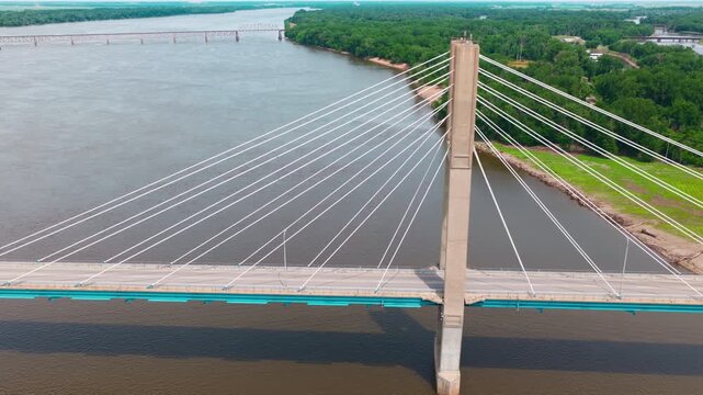 High angle drone flight past the concrete towers and suspension ropes of the Bayview Bridge crossing the muddy waters of the Midwest. Border betwen Illinois and Iowa. Quincy, Illinois, USA