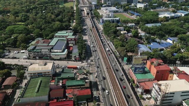 Aerial flyover of busy Epifanio de los Santos Avenue (EDSA) highway and MRT train passing by Metro Manila, Quezon City, Philippines