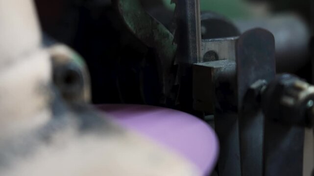 Slow motion footage of a bandsaw blade being sharpened by a grinding machine. Bright sparks fly from the metal during the industrial sharpening process.