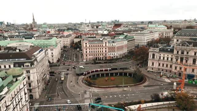 Wide aerial view of Karlsplatz, Vienna as a train passes by the sunken oval roadway pedestrian area.
