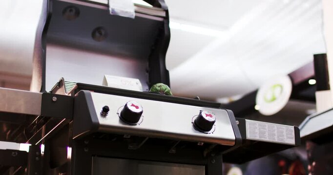 Low angle view of a modern black gas grill with an open lid on display in a retail store