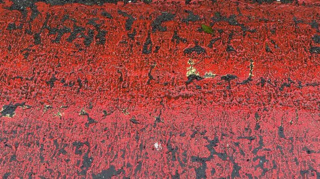 Background moving of red paint on floor weathered abstract road tar markings UK 4K