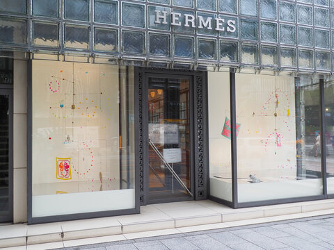 TOKYO, JAPAN - June 24, 2026: Front of Maison Hermes Ginza including window displays featuring hanging mobiles.