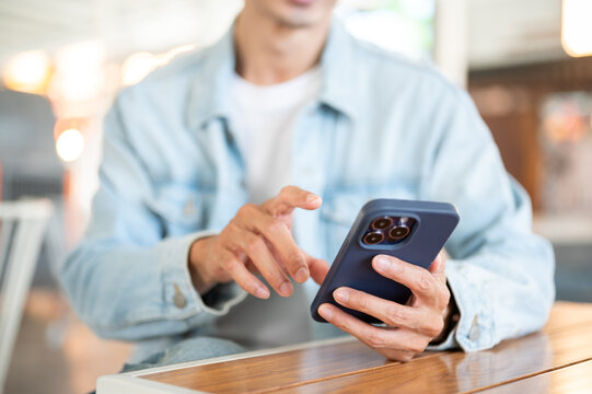 Close up of man's hand interacting with smartphone sitting at cafe table showcasing digital lifestyle