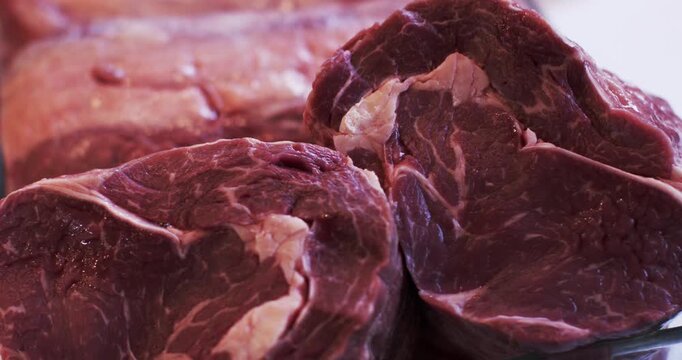 Close up view of raw marbled beef steaks stacked together on a white surface