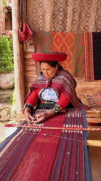 Peruvian woman in traditional clothing weaving a colorful textile using a handmade loom in cuzco