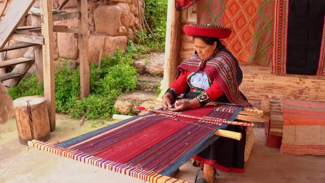 Peruvian senior woman weaving traditional colorful textiles on a backstrap loom in Peru