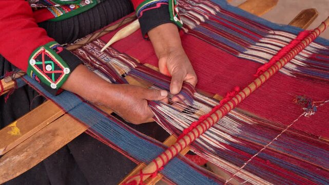 Close-up of indigenous woman weaving colorful textile on a traditional loom