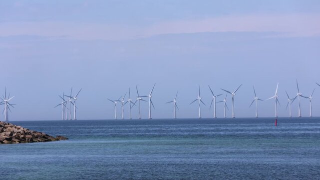 Wide angle video of offshore wind turbines at Lillgrund wind park in Oresund between Sweden and Denmark during a bright sunny day, renewable energy concept.