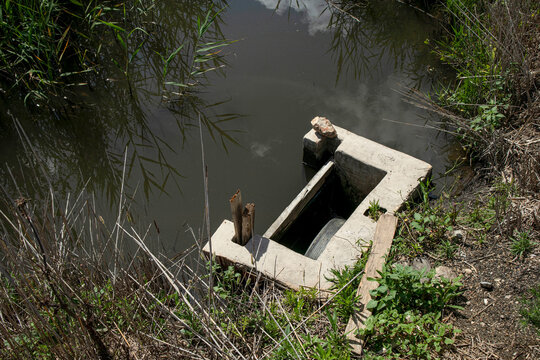 High angle view of a concrete irrigation sluice gate directing water into a canal in Pego Oliva Marsh rice fields of Valencia