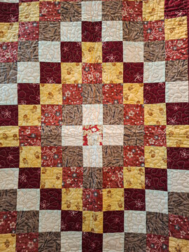 Bright patchwork quilt with floral and geometric patterns shows cozy home decor in warm tones from a top down view