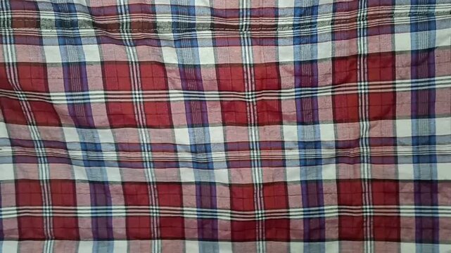Traditional kain pelikat featuring a classic woven plaid/checkered pattern in red, blue, white, and black tones. Lightweight fabric with a casual and traditional appearance, commonly used as a sarong 