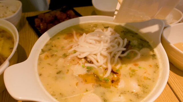 Adding Fresh Rice Noodles to Spicy Fish Ball Soup in Bangkok