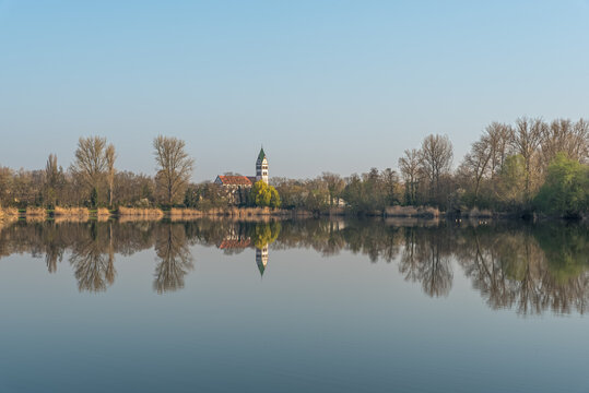 Fishing lake and St. Sebastian Church in morning light, Ketsch, Baden-Wuerttemberg, Germany