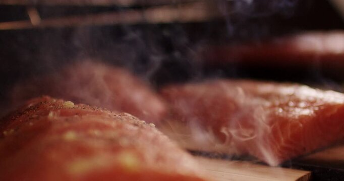Close up view of fresh salmon fillets with yellow spice mix smoking gently on a wooden plank
