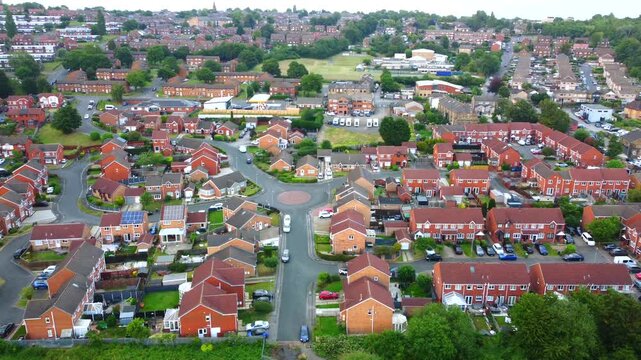Aerial view of a quiet residential neighborhood featuring rows of red brick houses, winding streets, and lush green gardens in Dewsbury, Dewsbury, United Kingdom.