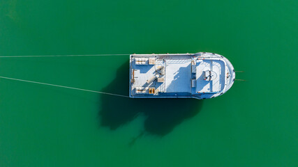 Top down aerial drone shot of a white service boat or small passenger ferry anchored in the green sea © Buğra Kaan Ersoy