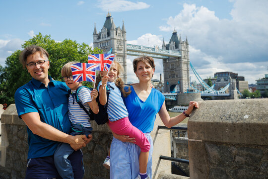Family with kids pose hold flags near Tower Bridge in London, UK