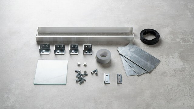 Hardware components including metal brackets and fasteners are organized on a gray surface for construction assembly.