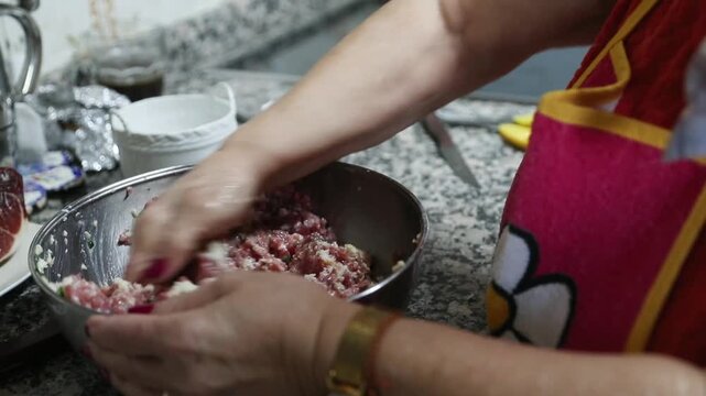  Mujer mayor mezclando ingredientes de alb&oacute;ndigas a mano en un taz&oacute;n. Abuela mayor amasando y mezclando ingredientes de alb&oacute;ndigas a mano en un taz&oacute;n. Cocina tradicional casera, aut&eacute;ntica senior.