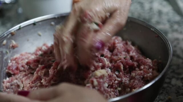  Mujer mayor mezclando ingredientes de alb&oacute;ndigas a mano en un taz&oacute;n. Abuela mayor amasando y mezclando ingredientes de alb&oacute;ndigas a mano en un taz&oacute;n. Cocina tradicional casera, aut&eacute;ntica senior.