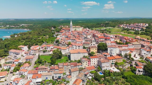 Drone half‑circle around Vrsar&rsquo;s hilltop old town, then turning and sliding to reveal the marina, nearby hotels, and the archipelago of islands and islets in bright Adriatic light. Istria, Croatia