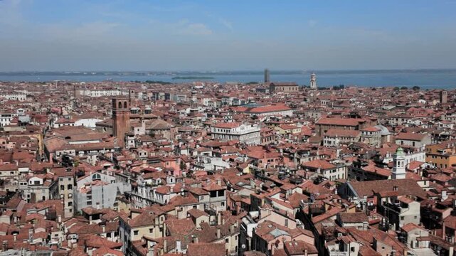 Panning video over traditional terracotta rooftops towards the Venetian lagoon on a sunny day in Venice, Italy.