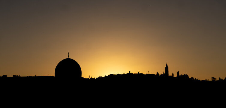 Silhouette of the iconic Dome of the Rock and city minarets against a vibrant golden sunset sky in Jerusalem