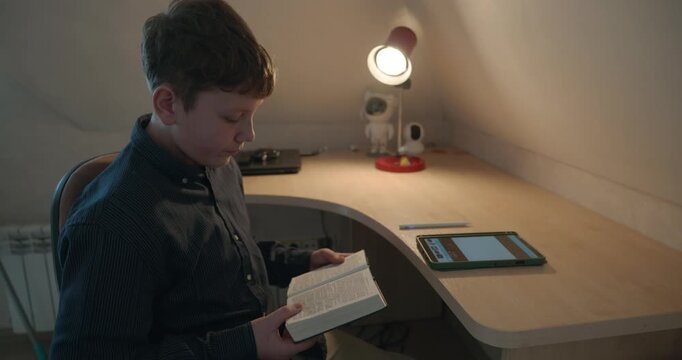 Kid Boy Read Bible Book Sitting at Desk Table in Room. 4K 10-bit