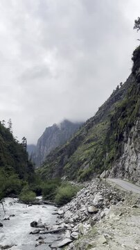 Mountain road with landslide debris beside river in Himalayas.