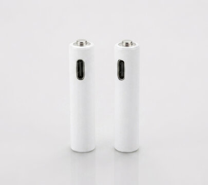Two white rechargeable AAA lithium batteries with USB-C ports and charging cable on a white background