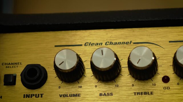 Guitar amplifier control panel with volume, bass, and treble knobs. Macro closeup of vintage style combo amp settings and audio tone controls. Music equipment, sound adjustment, and electric guitar